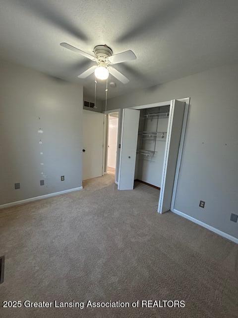 unfurnished bedroom featuring a textured ceiling, a closet, ceiling fan, and carpet flooring