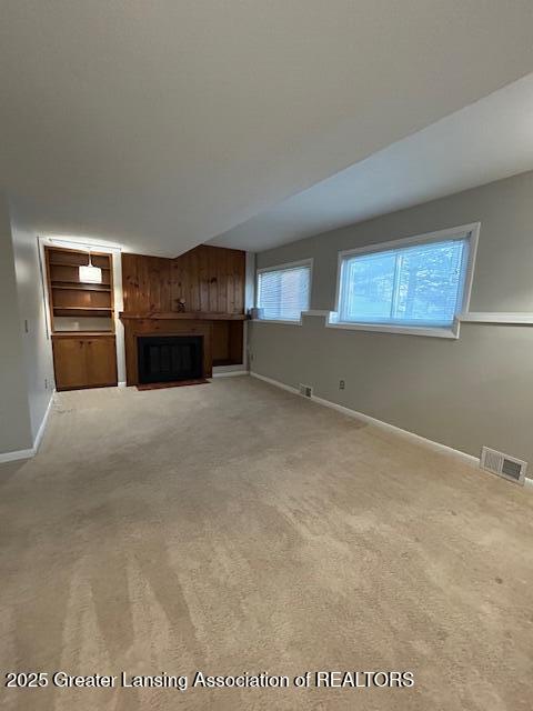 unfurnished living room with light carpet and wooden walls