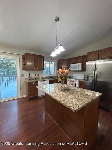 kitchen with pendant lighting, white appliances, dark hardwood / wood-style flooring, and a kitchen island