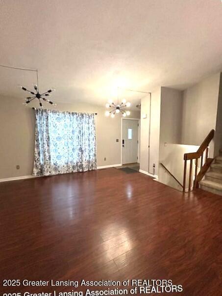 unfurnished living room featuring hardwood / wood-style flooring and an inviting chandelier