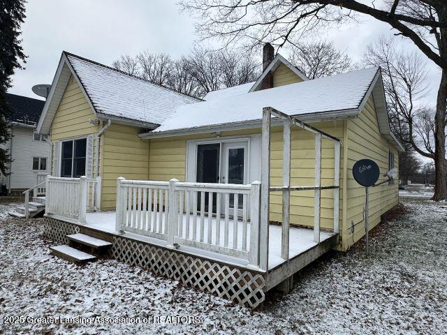 snow covered back of property with a deck