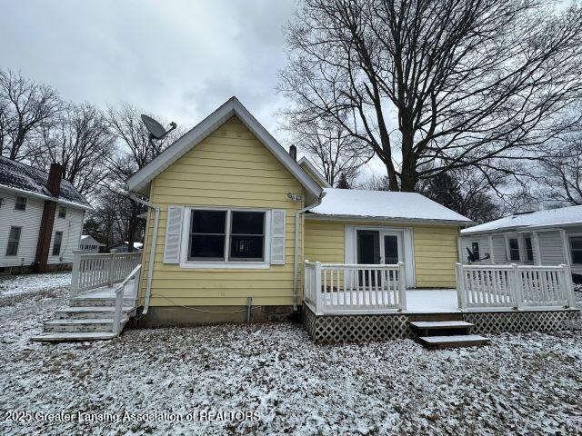 snow covered back of property with a deck