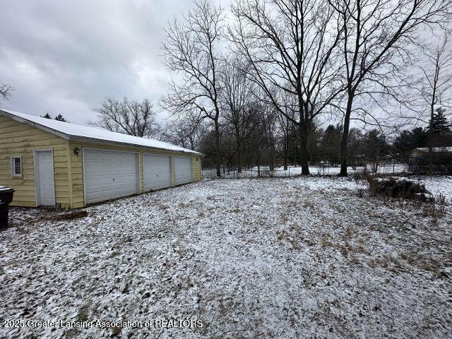 yard covered in snow with a garage and an outdoor structure