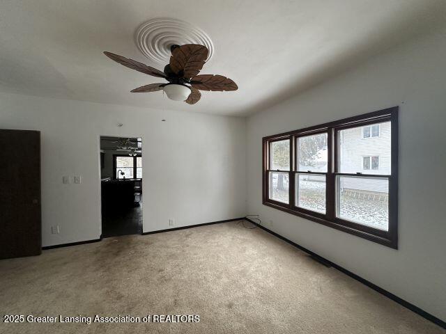 carpeted spare room with ceiling fan