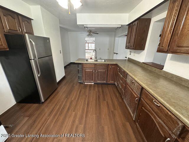 kitchen with sink, stainless steel fridge, kitchen peninsula, dark hardwood / wood-style flooring, and ceiling fan