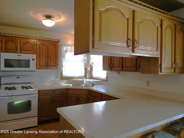 kitchen featuring white appliances, kitchen peninsula, and sink