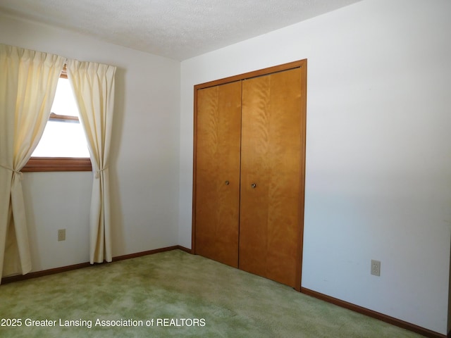 unfurnished bedroom featuring light carpet, a closet, and a textured ceiling