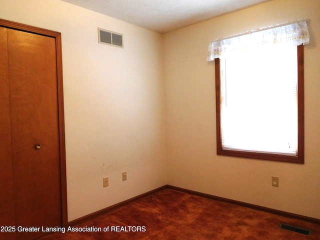 unfurnished room featuring dark carpet