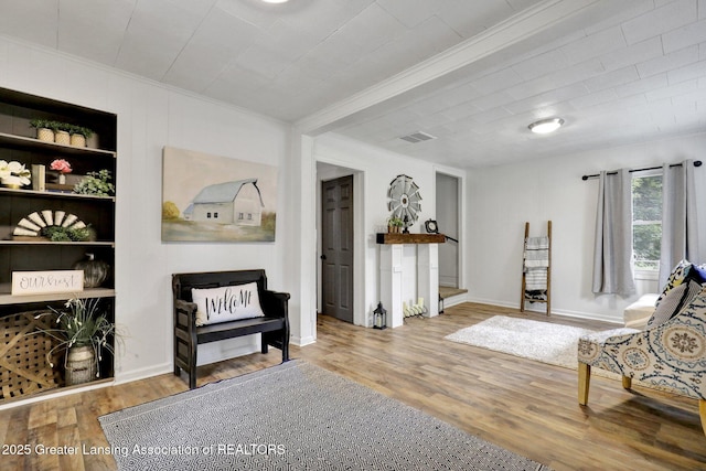 living area with hardwood / wood-style flooring and crown molding