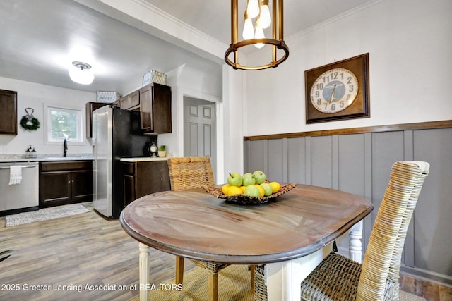 dining room with crown molding, sink, and light wood-type flooring