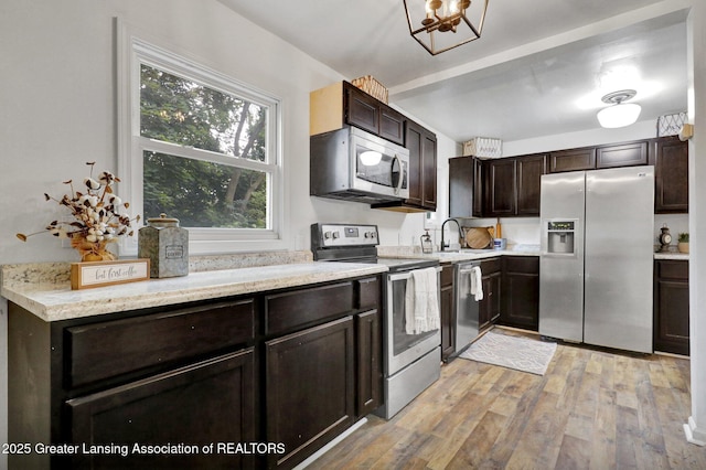 kitchen featuring stainless steel appliances, sink, dark brown cabinetry, and light hardwood / wood-style flooring