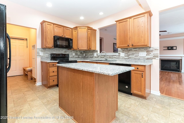 kitchen featuring sink, light stone counters, tasteful backsplash, black appliances, and a kitchen island