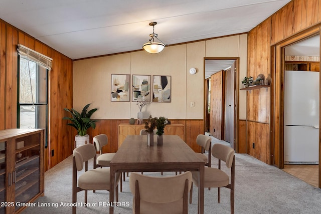 carpeted dining room with vaulted ceiling and wood walls