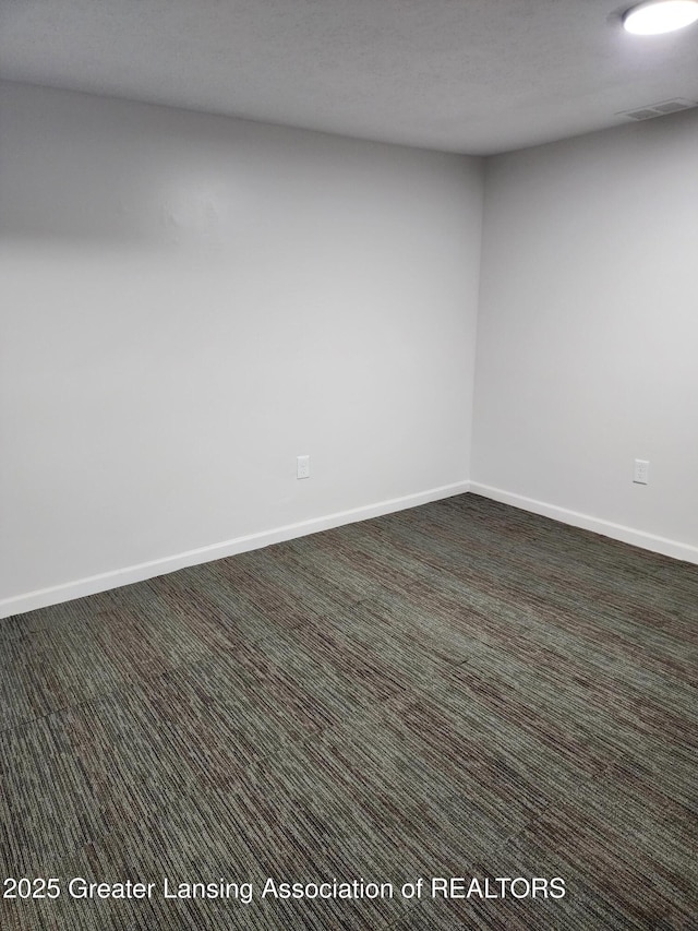 spare room with dark carpet