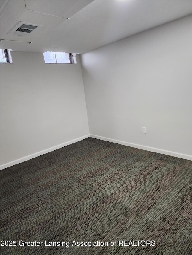 basement with plenty of natural light and dark colored carpet