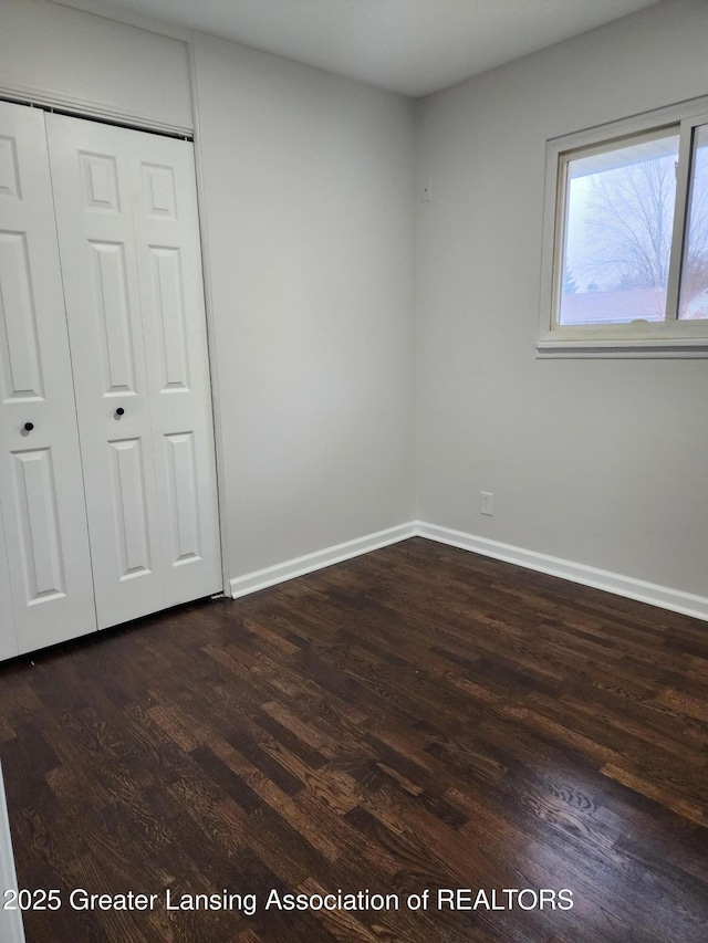 unfurnished bedroom with a closet and dark hardwood / wood-style floors