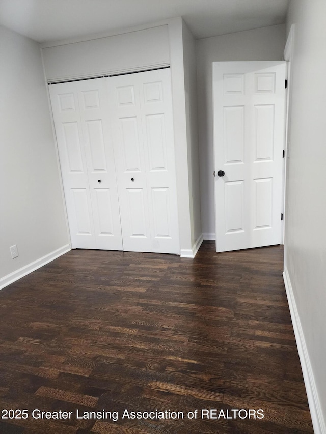 unfurnished bedroom with dark wood-type flooring and a closet