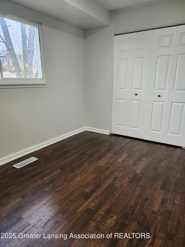 unfurnished bedroom with dark hardwood / wood-style flooring and a closet