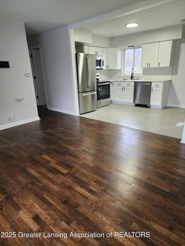 kitchen with stainless steel appliances, sink, hardwood / wood-style floors, and white cabinets