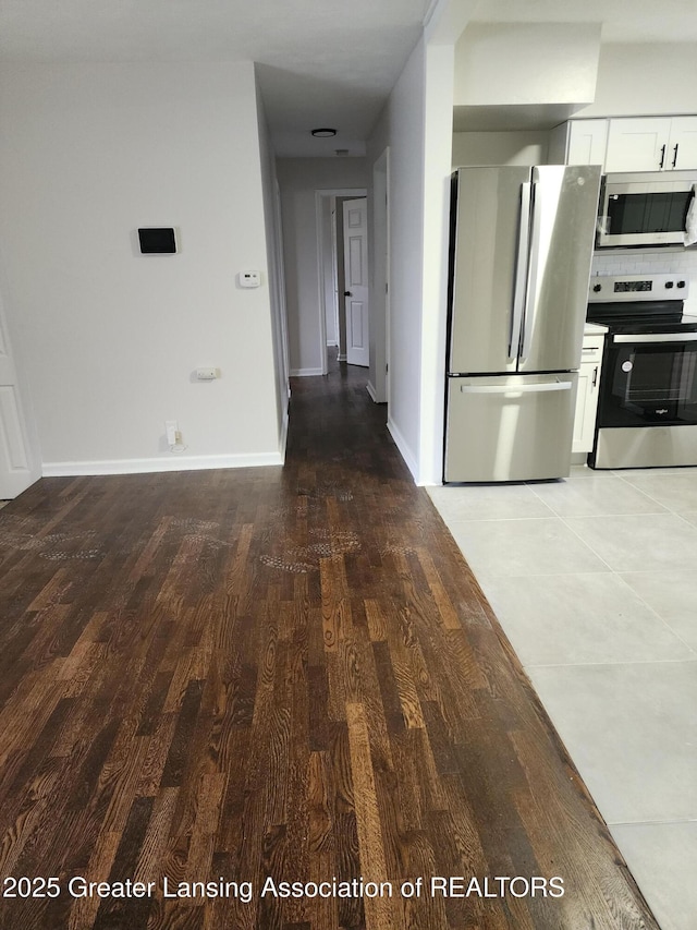 kitchen featuring hardwood / wood-style flooring, appliances with stainless steel finishes, tasteful backsplash, and white cabinets