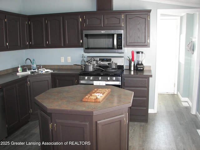 kitchen with sink, dark brown cabinets, appliances with stainless steel finishes, dark hardwood / wood-style flooring, and a kitchen island