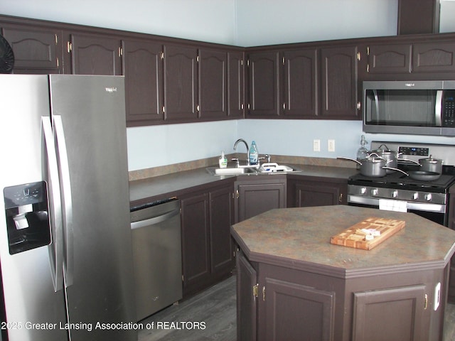 kitchen with a center island, appliances with stainless steel finishes, sink, and dark brown cabinetry