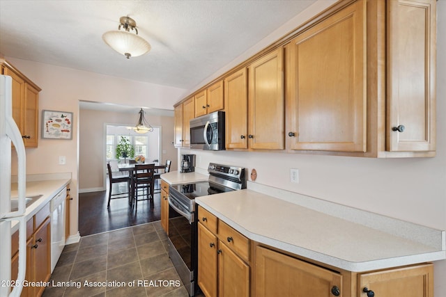 kitchen featuring appliances with stainless steel finishes, decorative light fixtures, and dark tile patterned flooring