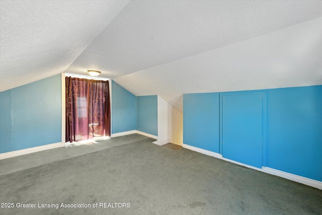 bonus room featuring dark colored carpet, lofted ceiling, and a textured ceiling