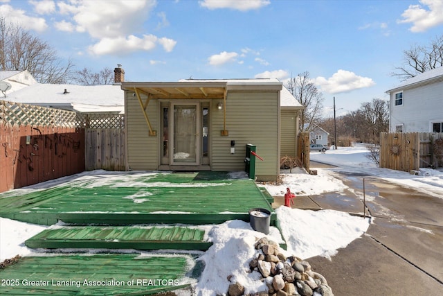 snow covered back of property with a deck