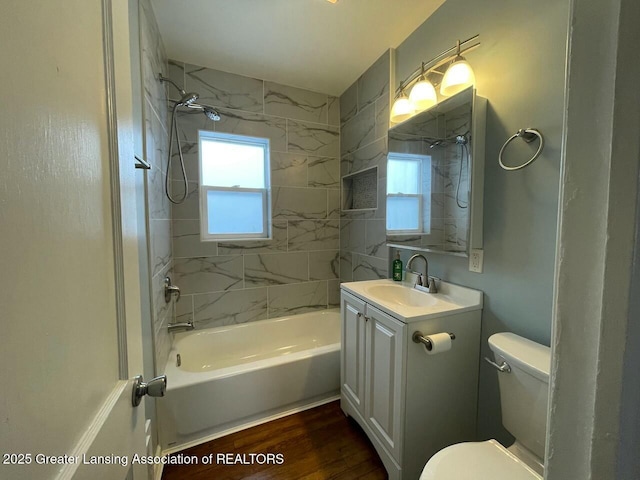 full bathroom with tiled shower / bath combo, vanity, a healthy amount of sunlight, and hardwood / wood-style floors