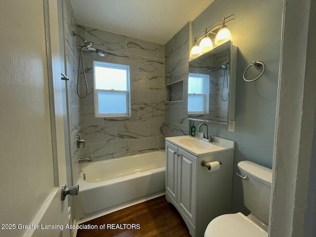 full bathroom with hardwood / wood-style flooring, tiled shower / bath, vanity, and toilet