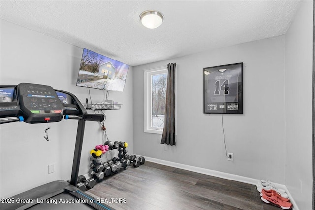 exercise area featuring dark wood-type flooring and a textured ceiling