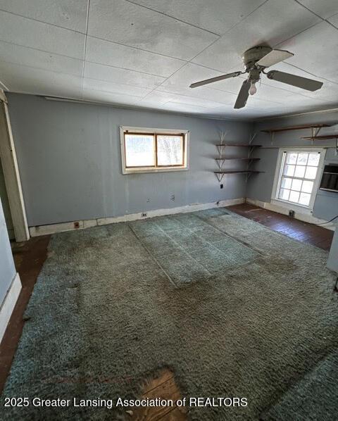 carpeted empty room featuring a wealth of natural light and ceiling fan