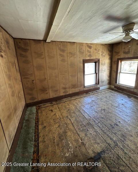 spare room featuring dark wood-type flooring, ceiling fan, and wood walls