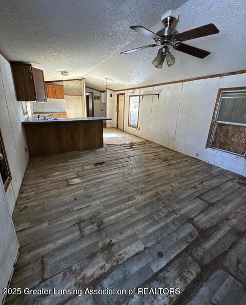 interior space featuring lofted ceiling, a textured ceiling, dark hardwood / wood-style floors, kitchen peninsula, and ceiling fan