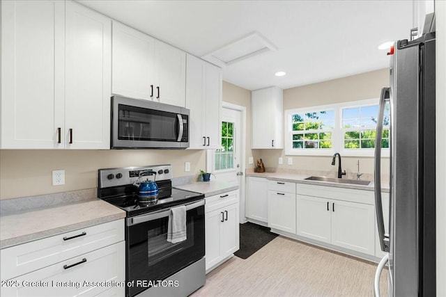 kitchen with appliances with stainless steel finishes, sink, and white cabinets