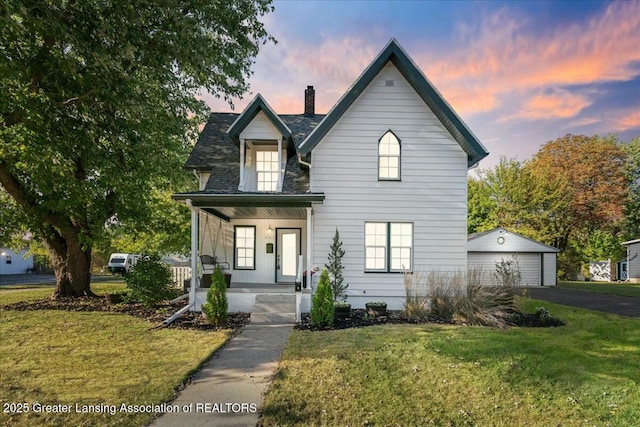 front of property with a garage, an outdoor structure, covered porch, and a lawn