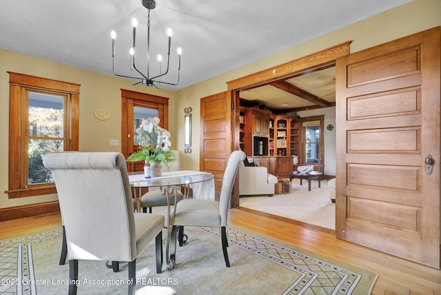 dining area with beam ceiling, an inviting chandelier, and light hardwood / wood-style floors