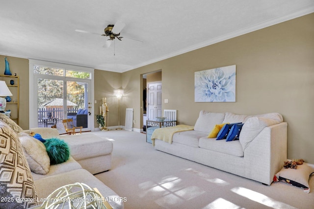 carpeted living room with crown molding and ceiling fan