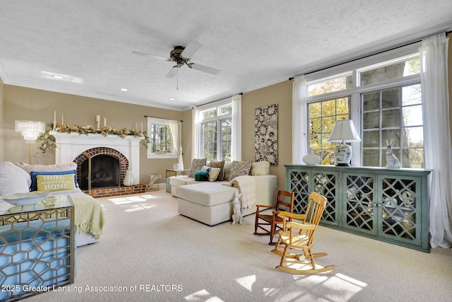 living room with a fireplace, carpet floors, ceiling fan, crown molding, and a textured ceiling