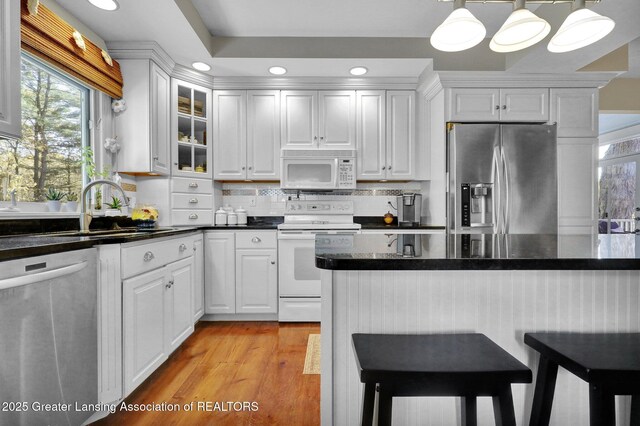 kitchen featuring a kitchen bar, sink, white cabinetry, appliances with stainless steel finishes, and pendant lighting