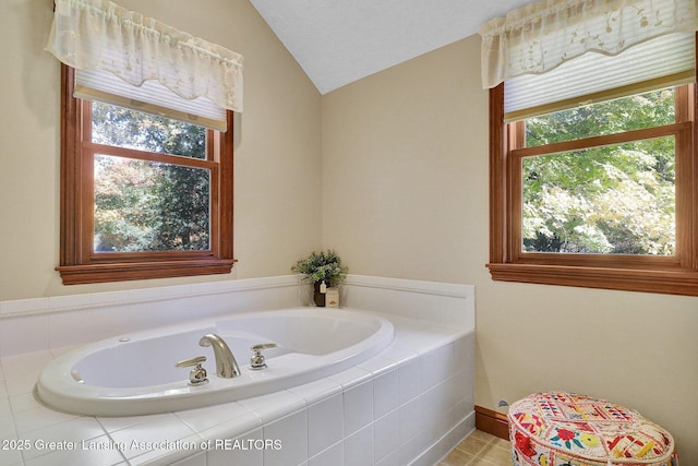 bathroom featuring tiled tub and lofted ceiling