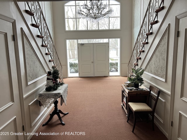 foyer with carpet, a towering ceiling, and an inviting chandelier