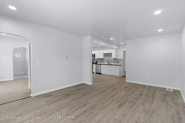 unfurnished living room featuring sink and light hardwood / wood-style flooring