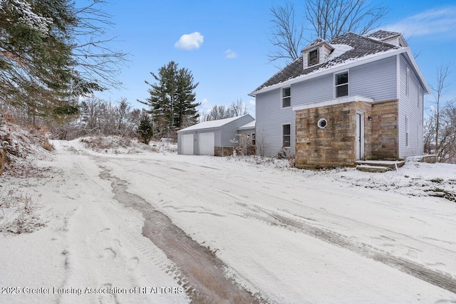 snow covered property featuring an outbuilding and a garage