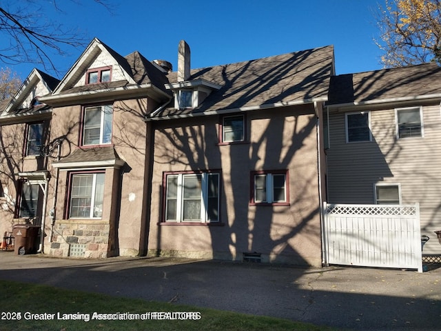 view of side of home featuring stucco siding, stone siding, and a chimney