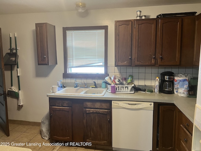 kitchen featuring white dishwasher, sink, tasteful backsplash, and dark brown cabinetry