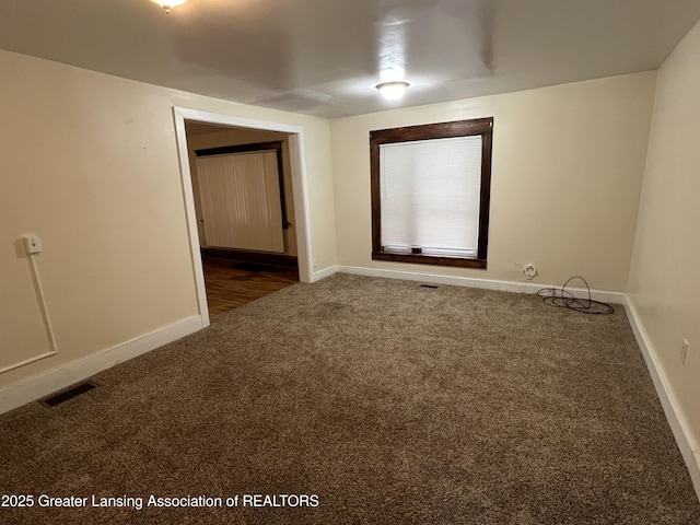 unfurnished room with dark colored carpet