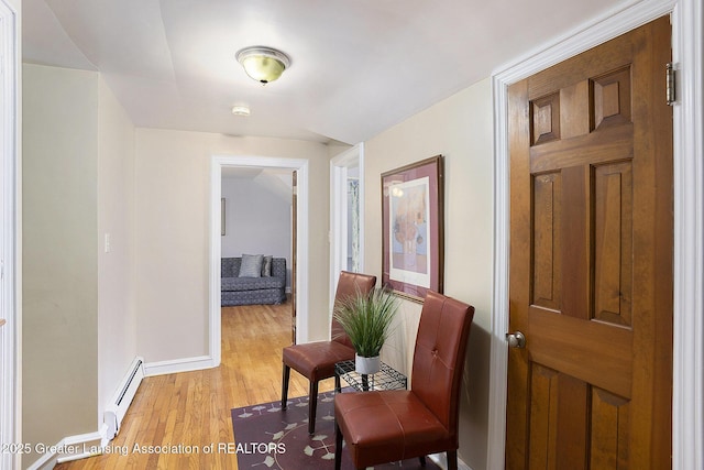 hall with baseboard heating and light hardwood / wood-style flooring