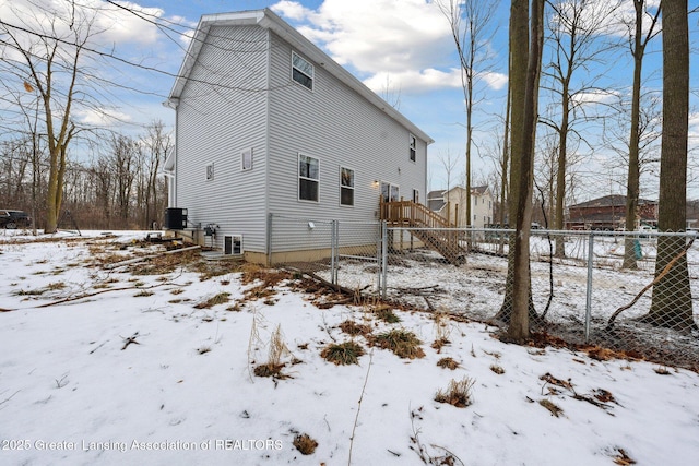 snow covered rear of property with central air condition unit